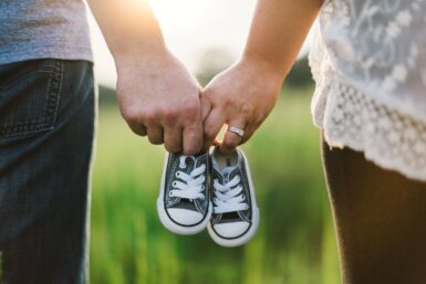 un homme et une femme de dos tenant dans leurs mains une paire de chaussures pour bébé